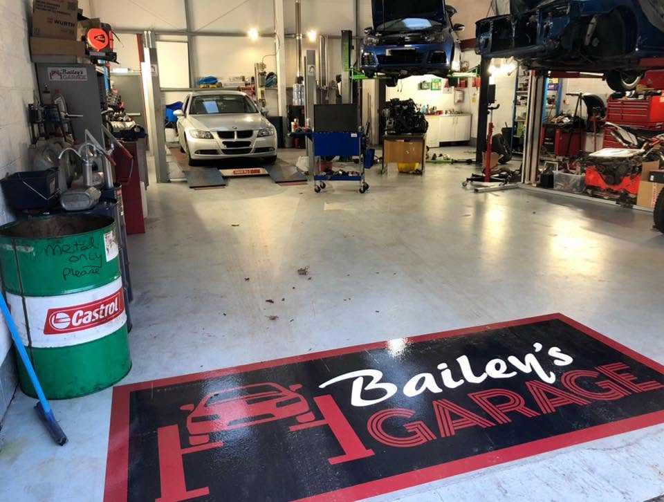 A car on the ramps beside the painted Bailey's Garage floor logo